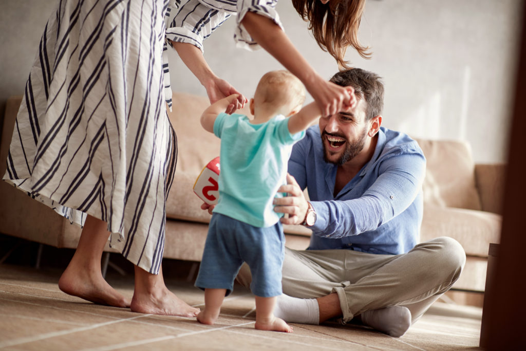 Bild von Babys ersten Schritten mit Hilfe von Mama und Papa