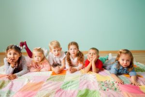 Bild von vielen Kindern auf einer Patchworkdecke