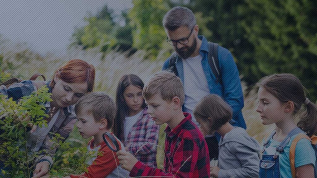 Auf dem Bild sind Kinder und zwei Erwachsene in der Natur zu sehen